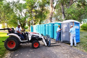 Huntley Project Lions Club member Roger Bender, Left, driving the tractor with Dan Krum, middle, and Lyle Hill, right, preparing for this weekend's Homesteader Days were at work Tuesday night placing 44 portable outhouses around Homesteader Park, where events begin Friday with an outdoor concert featuring the Gatlin Brothers, Craig Morgan and Bucky Beaver Ground Grippers. (Jonathan McNiven photo)